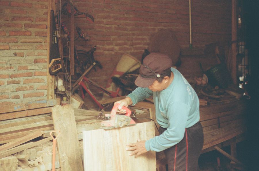 Tischler hobelt ein Holzbrett an der Werkbank